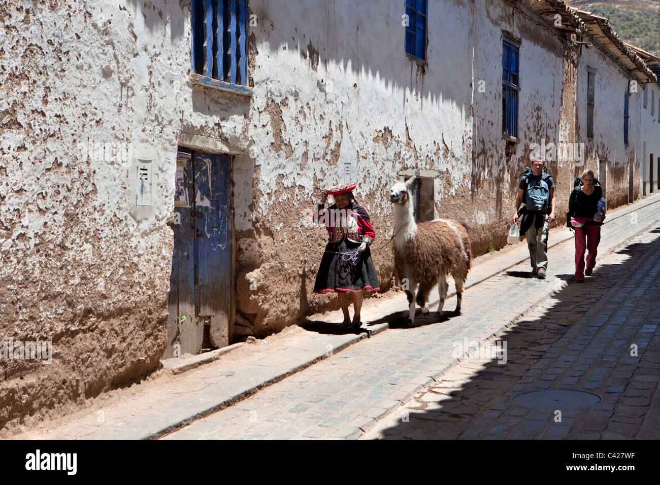 Peru, Cusco, Cuzco, Old Indian woman with llama and backpacker couple in San Blas district. UNESCO World Heritage Site. Stock Photo