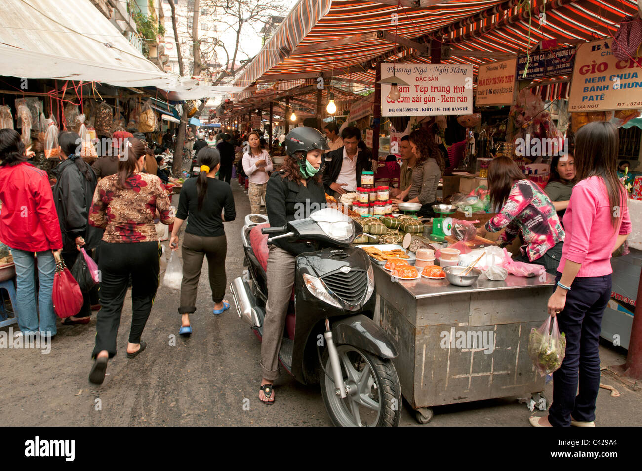 A Vietnamese lady shopping on her moped in one of Hanoi's many daily food markets in Vietnam Stock Photo