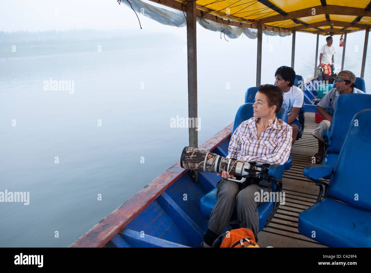 Peru, Boca Manu, Manu National Park, UNESCO World Heritage Site, River Rio Madre de Dios. Indian guides and tourist in boat. Stock Photo