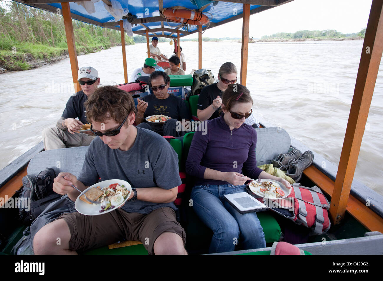 Peru, Boca Manu, Manu National Park, UNESCO World Heritage Site, River Rio Madre de Dios. Tourists in boat having lunch. Stock Photo