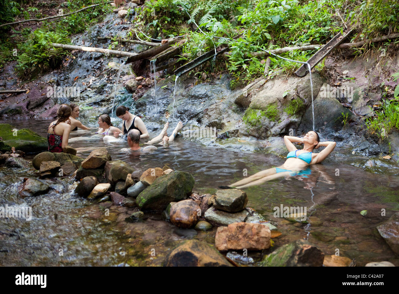 Peru, Cruz de Mayo, Manu National Park, Pantiacolla mountains. Tourists relaxing in stream of hot springs. Stock Photo