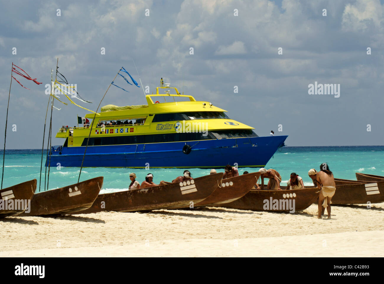 Traditional Mayan canoes with Cozumel ferry in background, Playa del Carmen, Riviera Maya, Quintana Roo, Mexico Stock Photo
