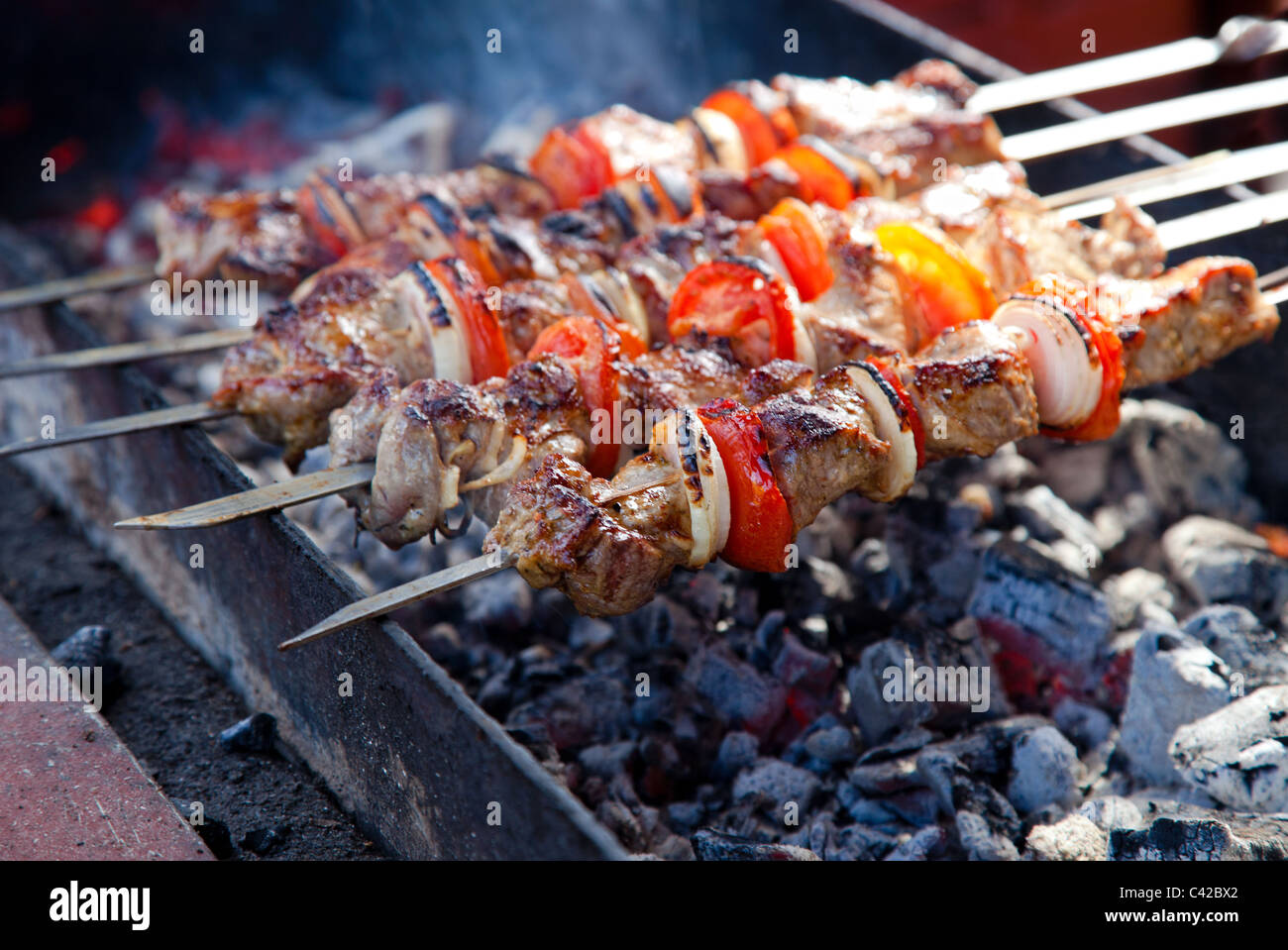 Juicy slices of meat with sauce prepare on fire (shish kebab). Stock Photo