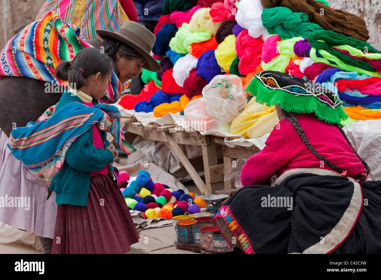 Peru, Huancarani, Woman and child in front of wool for sale on market. Stock Photo