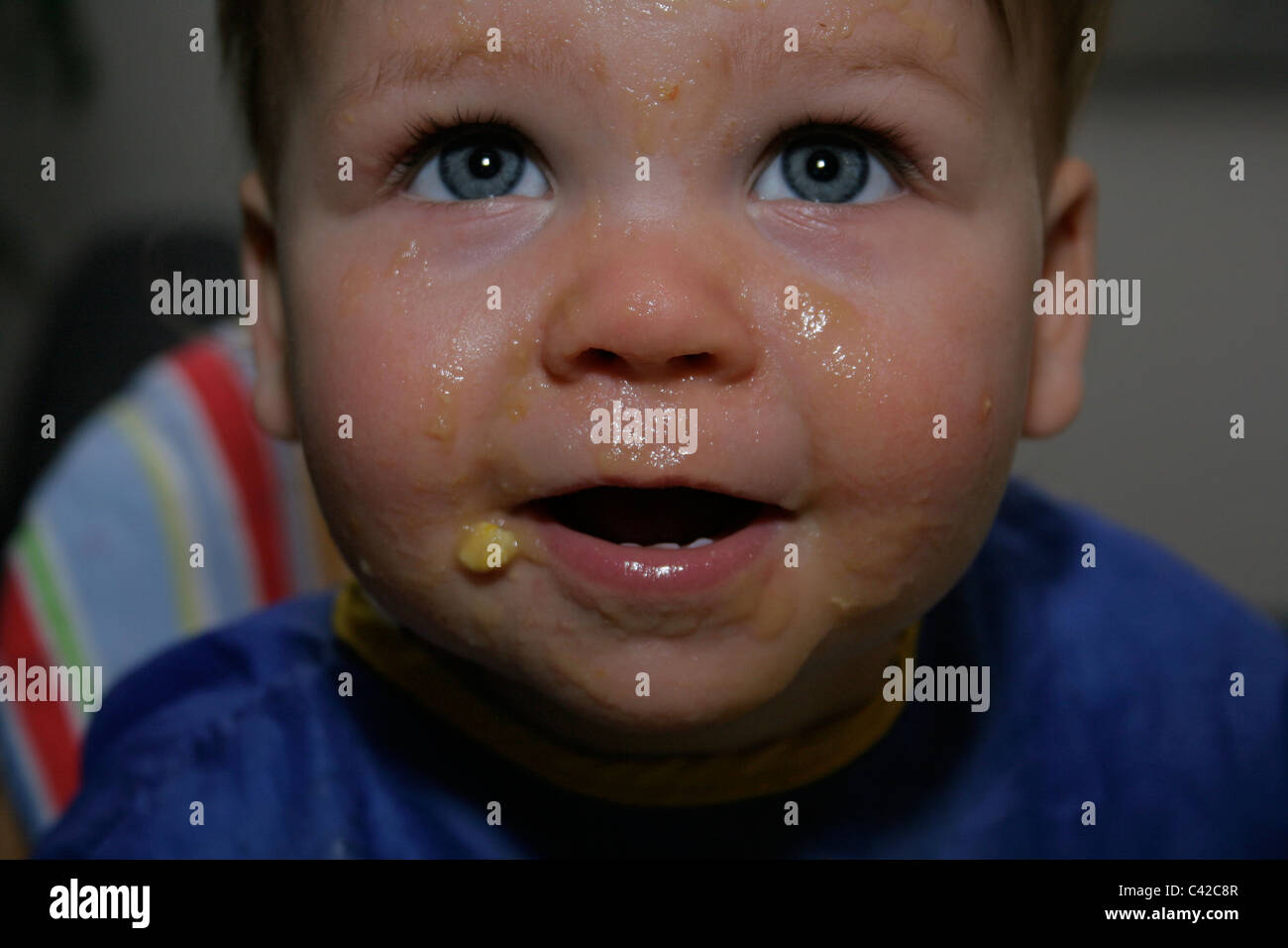 Close up of young child with food all over her face Stock Photo