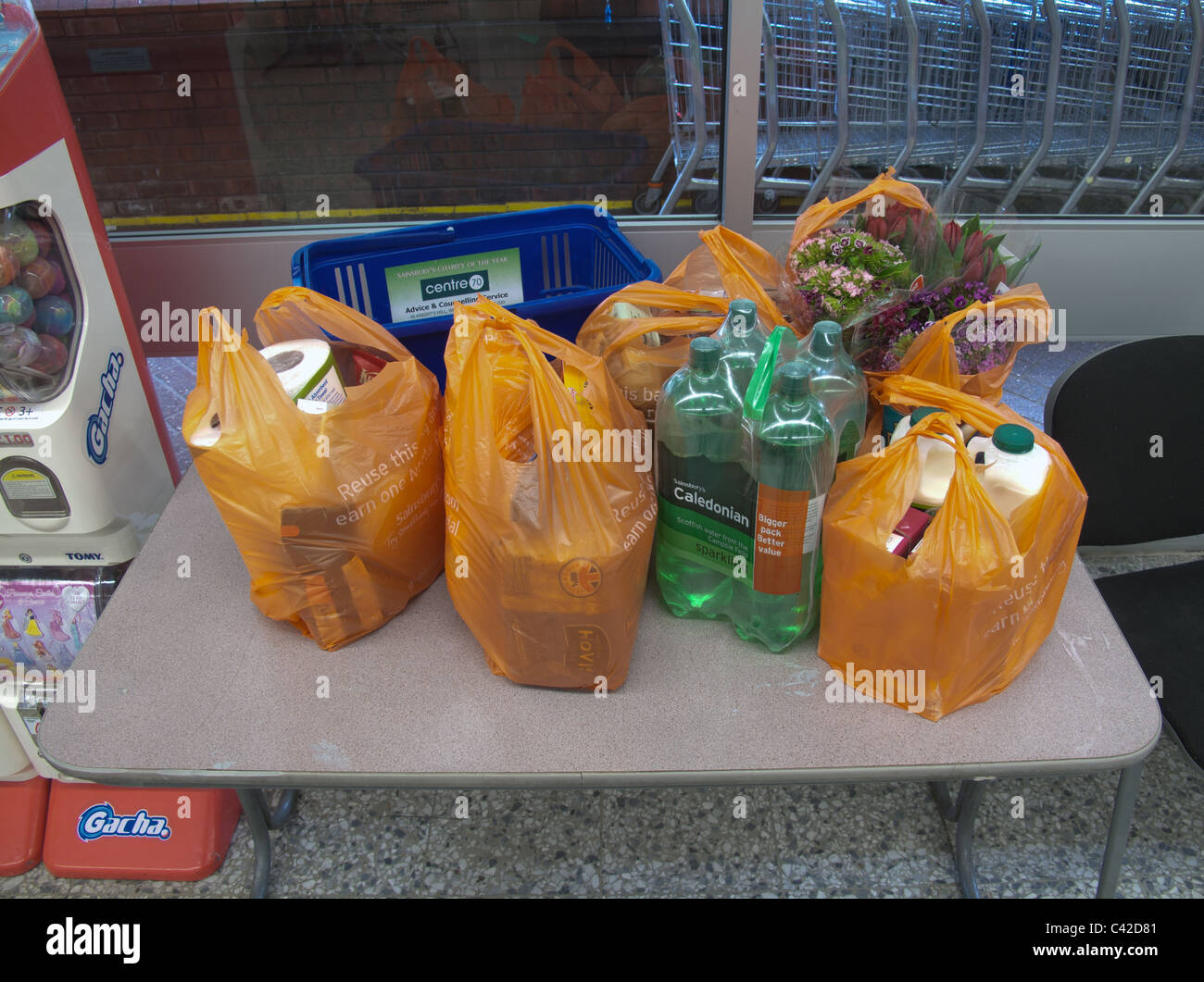 Groceries and flowers in supermarket shopping bags on a table in the store Stock Photo