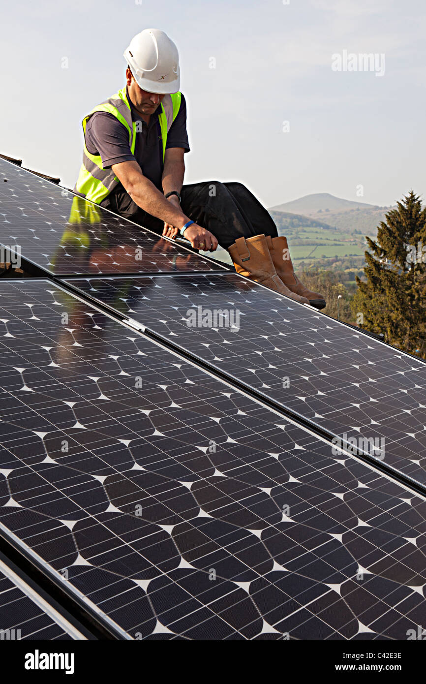 Man fitting solar pv panels to house roof Wales UK Stock Photo Alamy