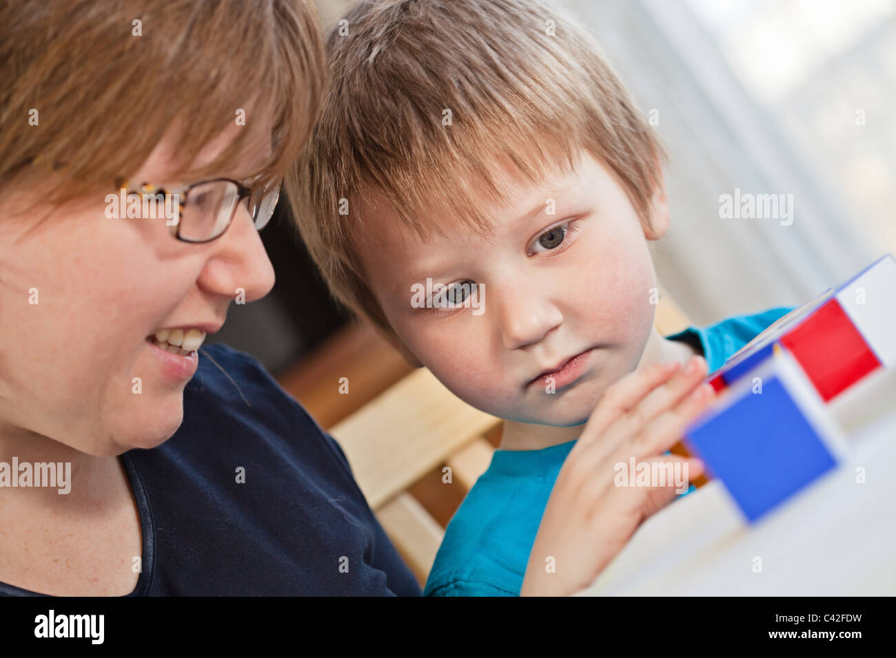 Mother and her little son playing colorful toys at home Stock Photo