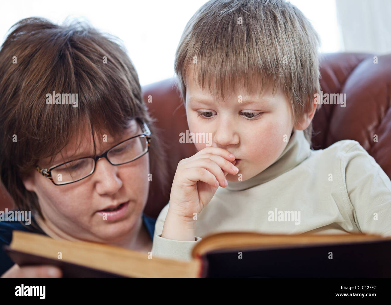 Mother and her little child reading a book together Stock Photo