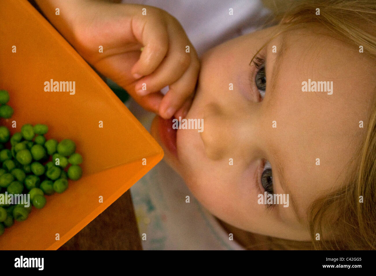 Young girl happily eating peas Stock Photo Alamy