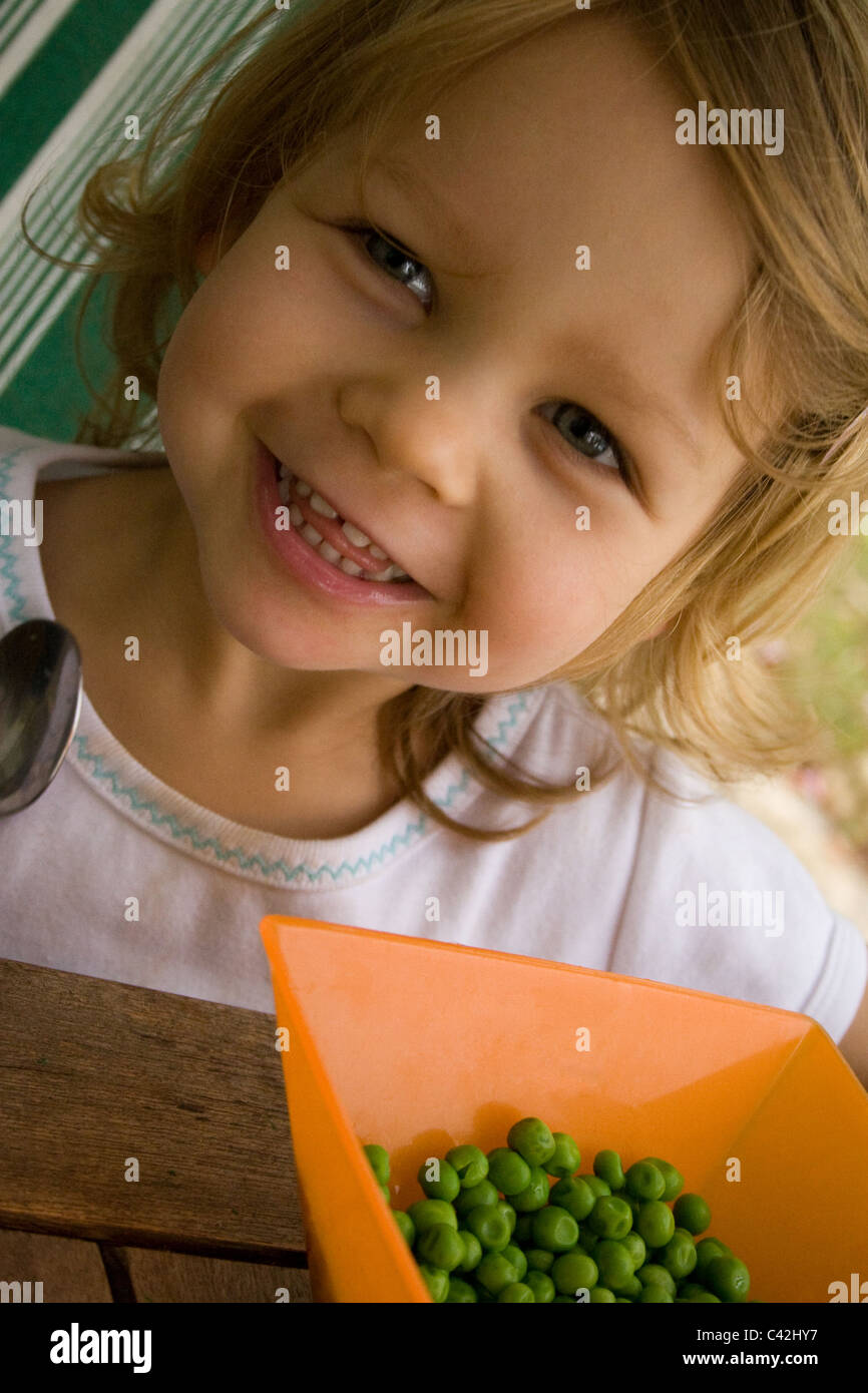 Young girl happily eating peas Stock Photo Alamy