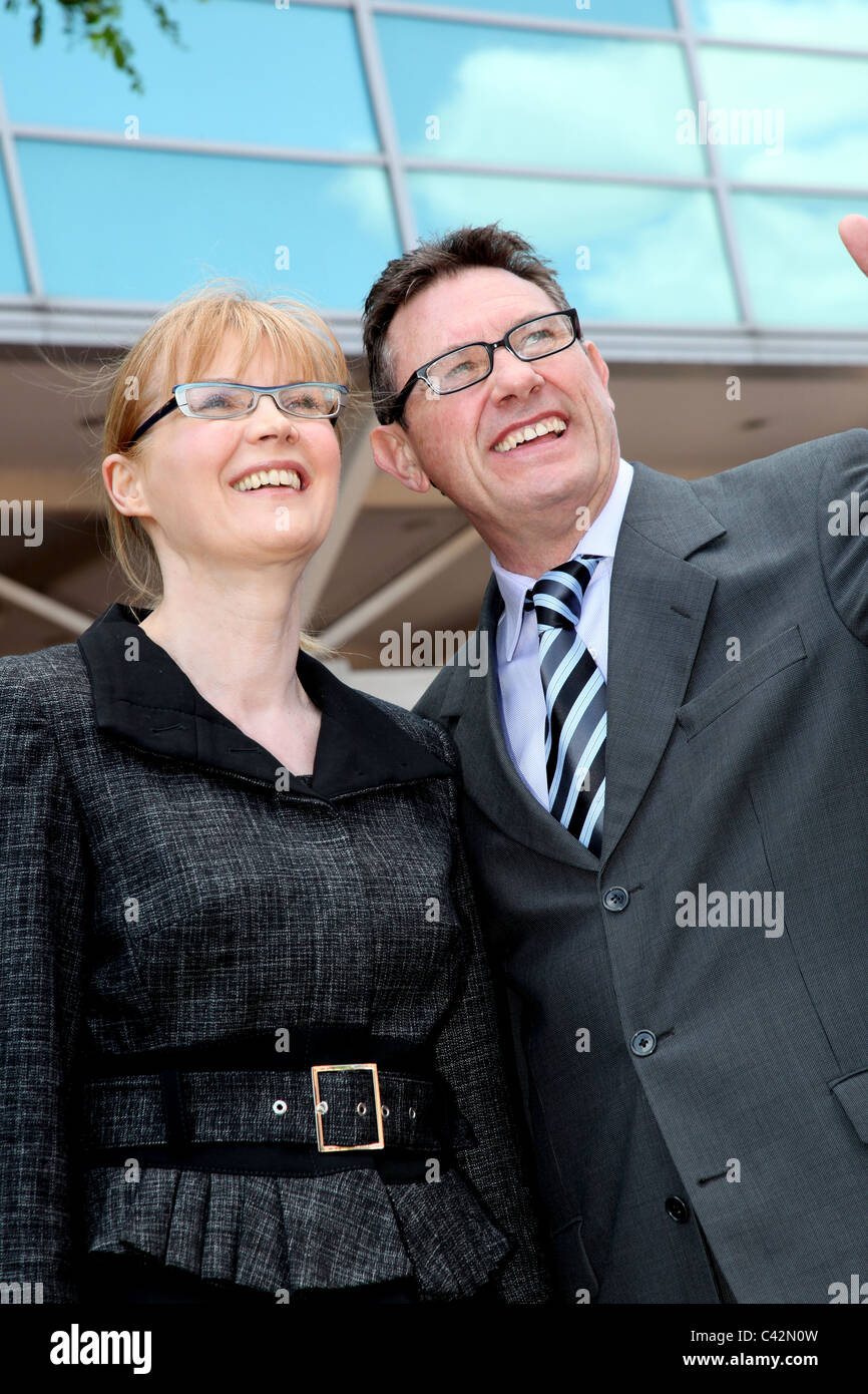 Mature business woman and man wearing glasses, outside smiling. Stock Photo