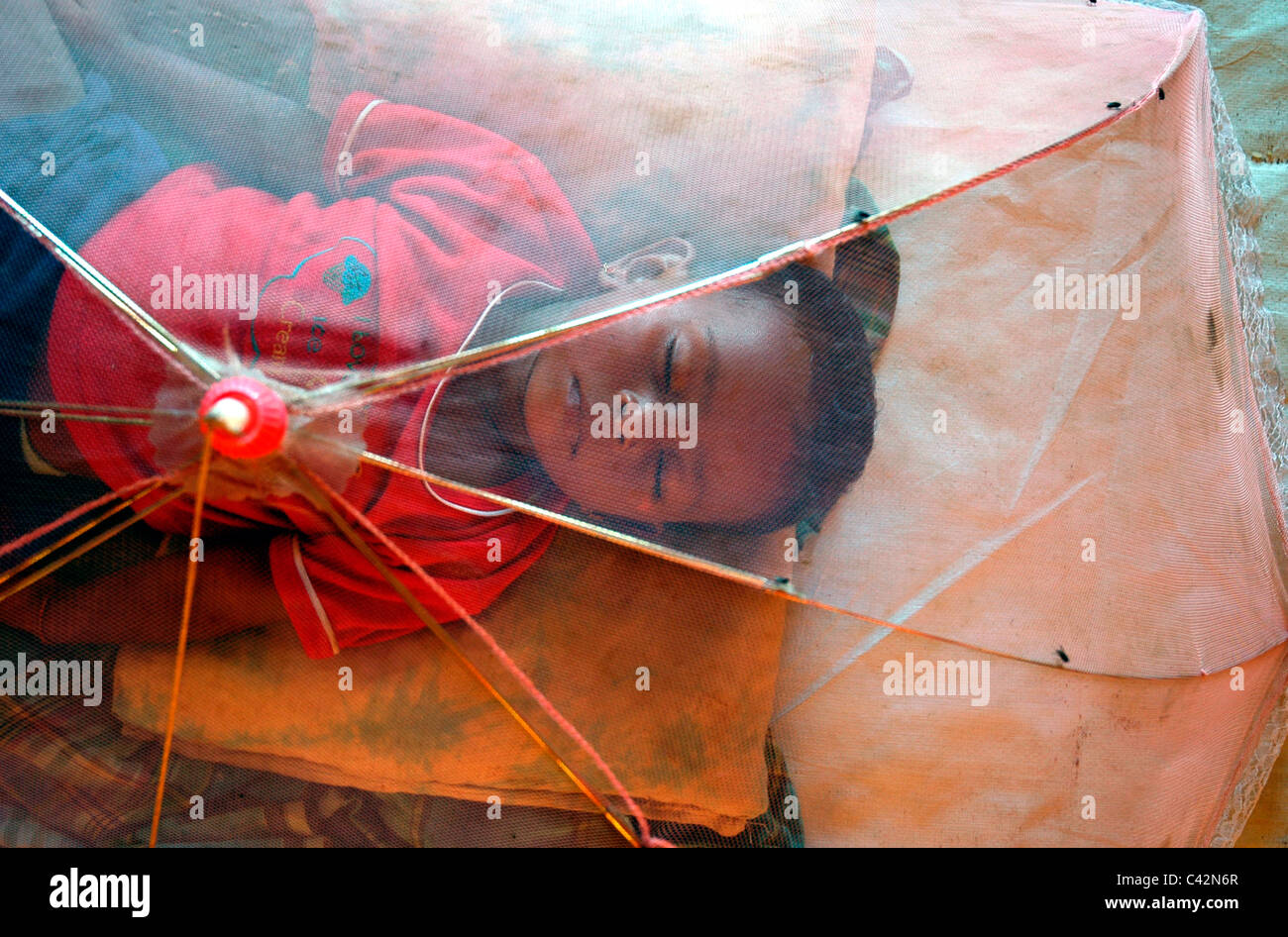 A child asleep beneath a mosquito net for families displaced by the