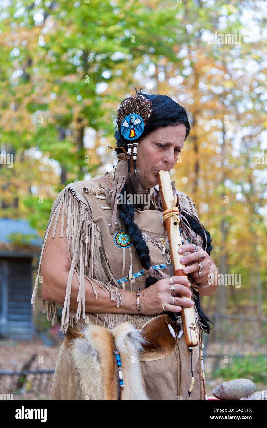 Woman dressed as Native American Indian plays hand made wooden flute at Billie Creek Village in Rockville, Indiana, USA Stock Photo
