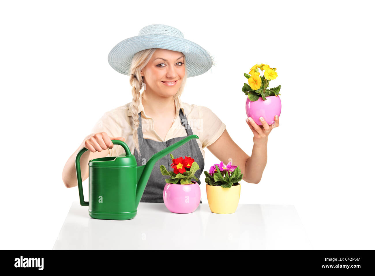 A smiling female gardener posing with flower pots and watering can ...
