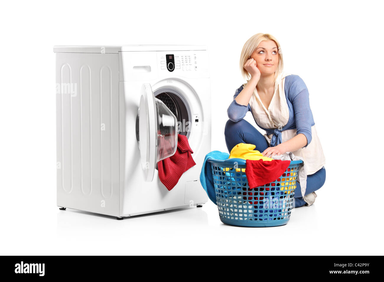 A young woman in thoughts with clothes seated next to a washing machine Stock Photo