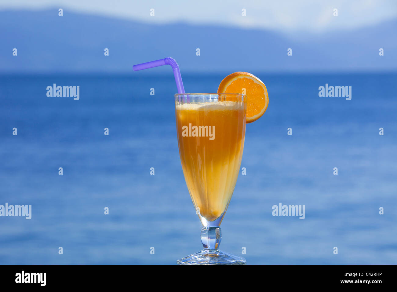 A glass of freshly squeezed orange juice with a lilac straw Stock Photo