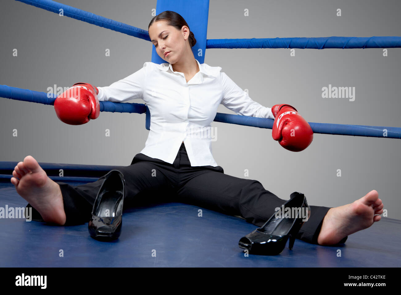 Portrait of tired businesswoman in boxing gloves sleeping on boxing