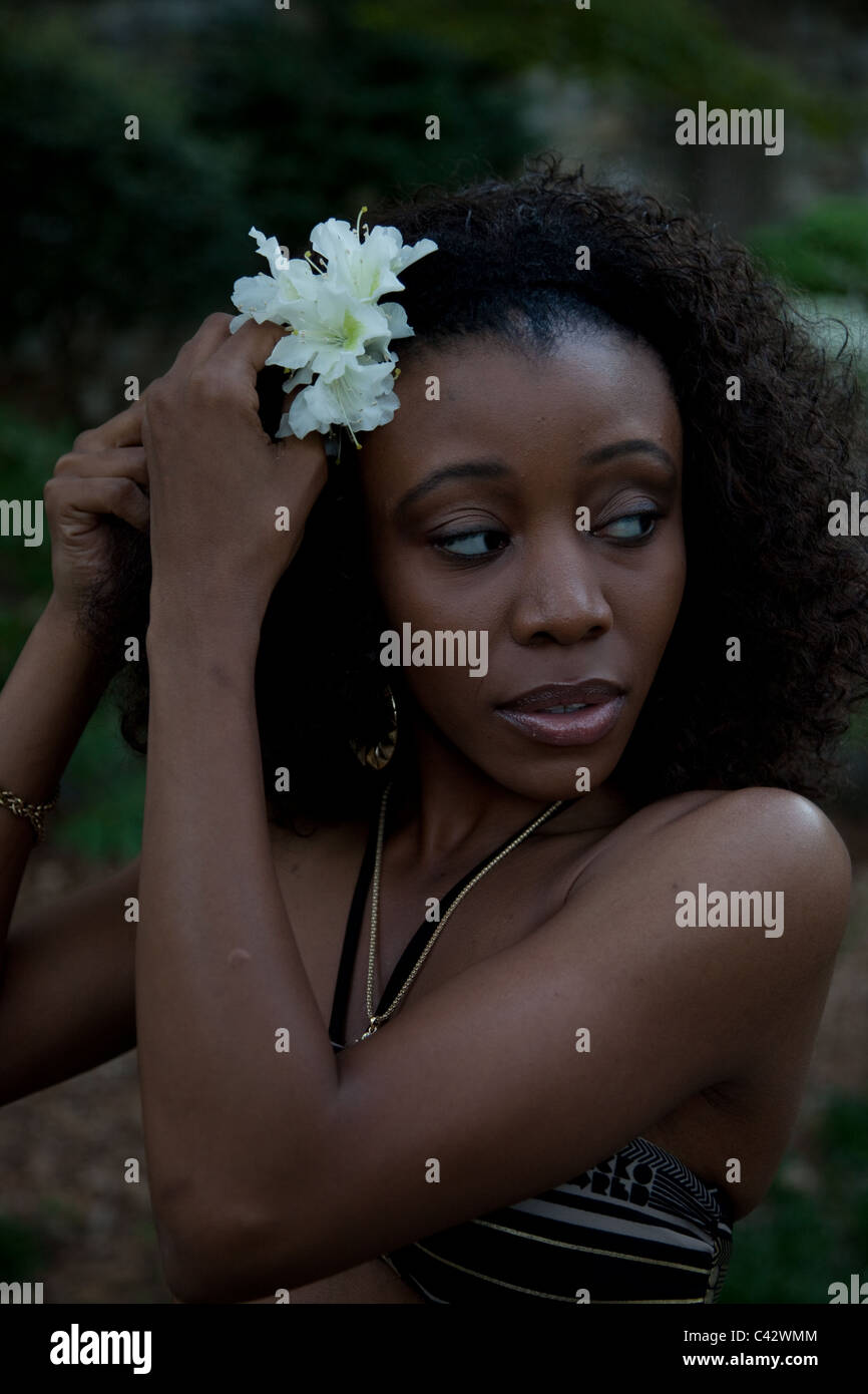 Lovely black woman, putting a white flower in her hair Stock Photo - Alamy