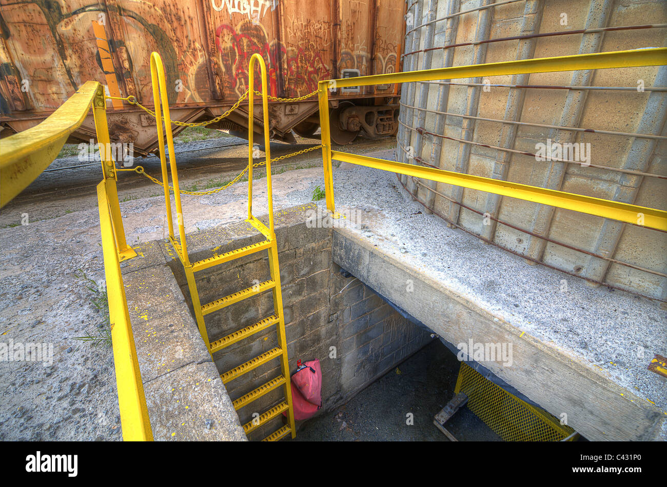 Ladder descending below ground at a gritty factory. Stock Photo