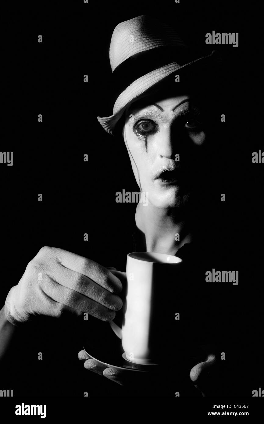 Portrait of terrible mime clown holding white cup Stock Photo