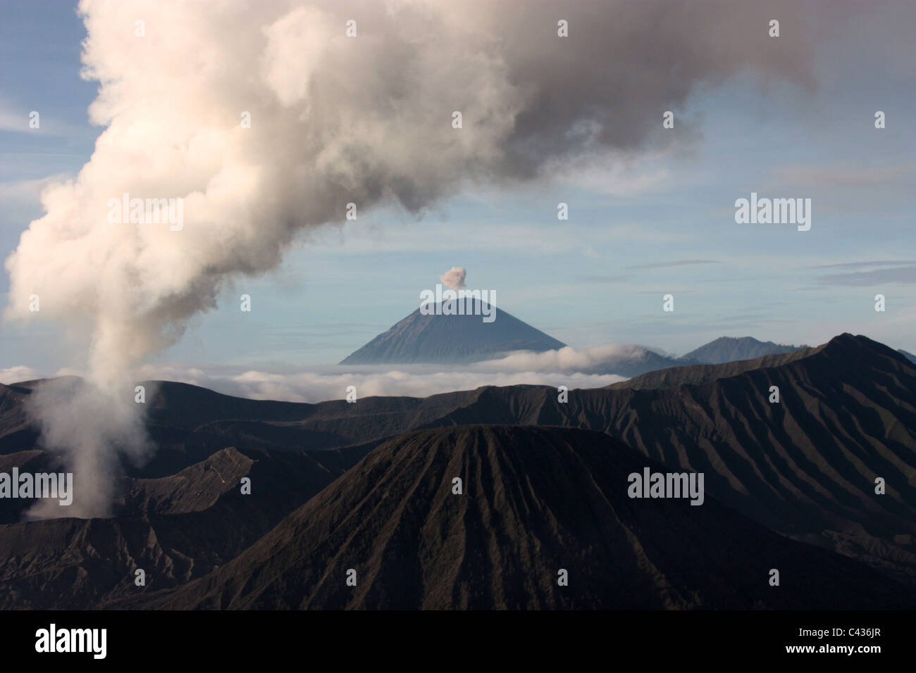 Iconic Mount Bromo in an active state with the smoking cone of Mount Semeru Stock Photo