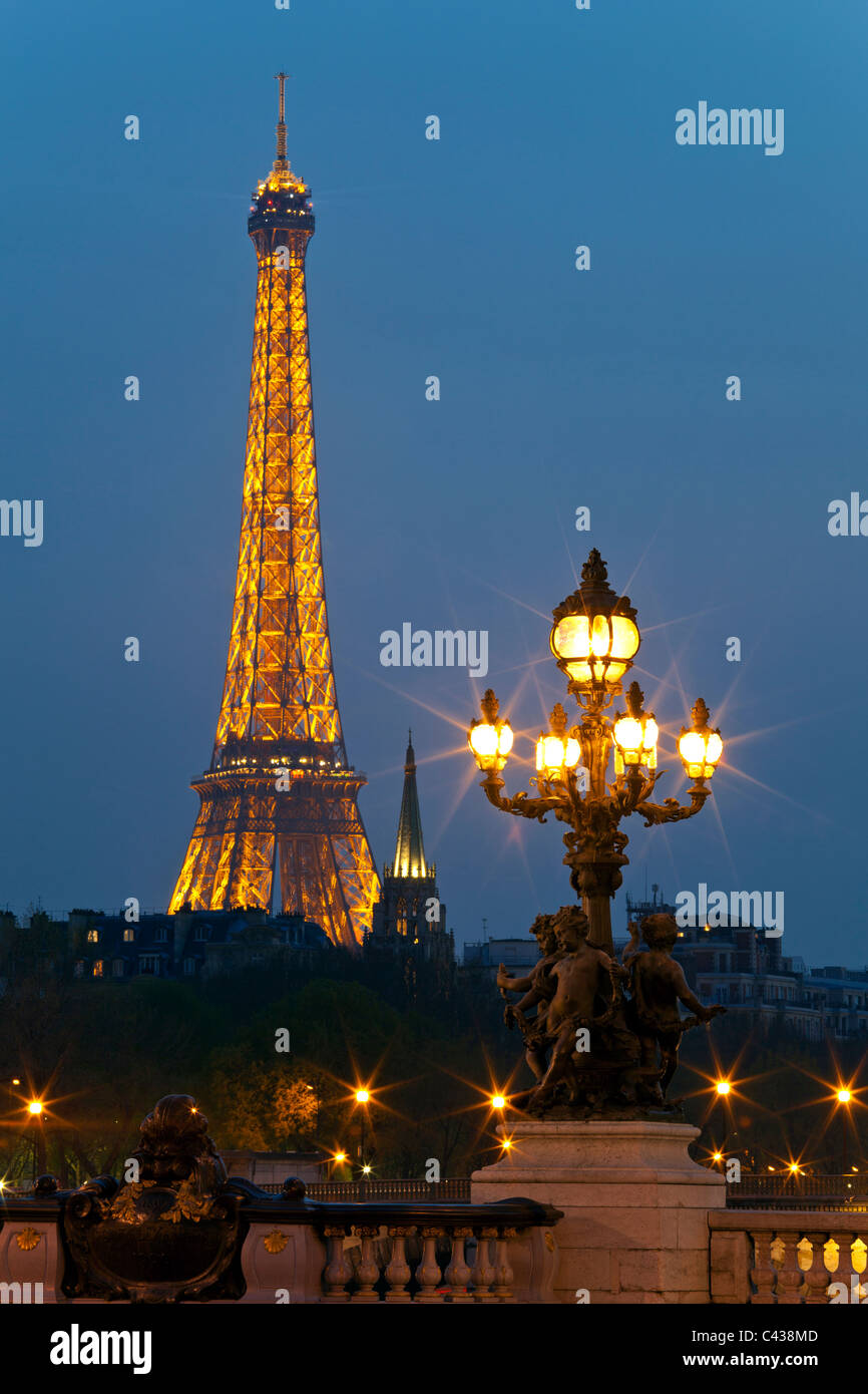 Lamppost on the bridge of Alexander III, against the backdrop of the Eiffel Tower at night. Paris, France. Stock Photo