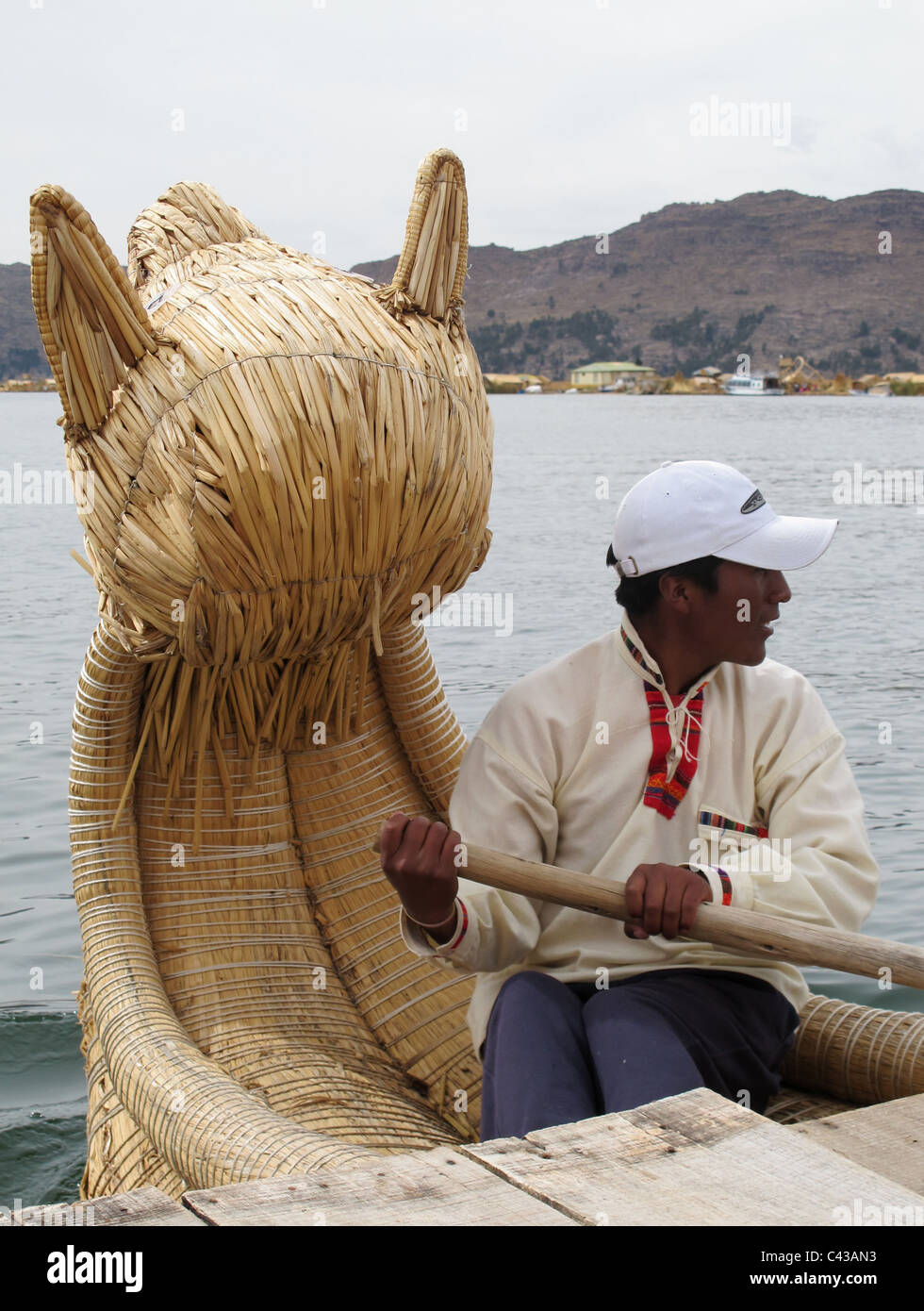 Uro man rowing his reed boat with dragon head for guests, lake titicaca, Peru Stock Photo