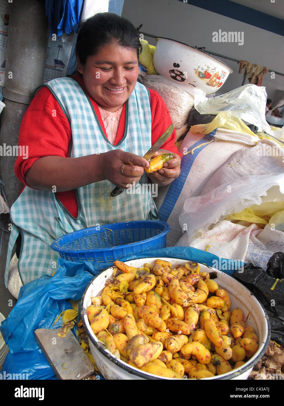Smiling woman cleaning root tuber, vegetable market, Ollantaytambo, Peru Stock Photo