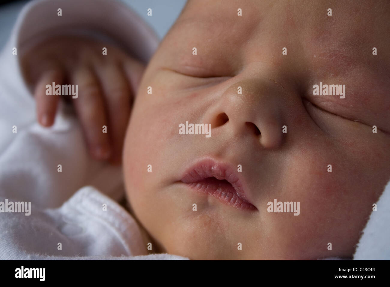 4 day old baby sleeps peacefully at home, with hand poised in the air Stock Photo