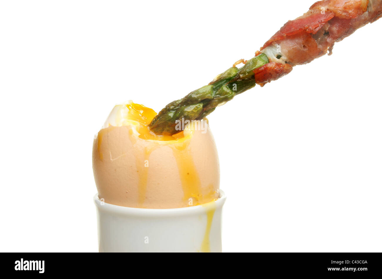Pancetta wrapped asparagus spear dipped in the yolk of a soft boiled egg Stock Photo