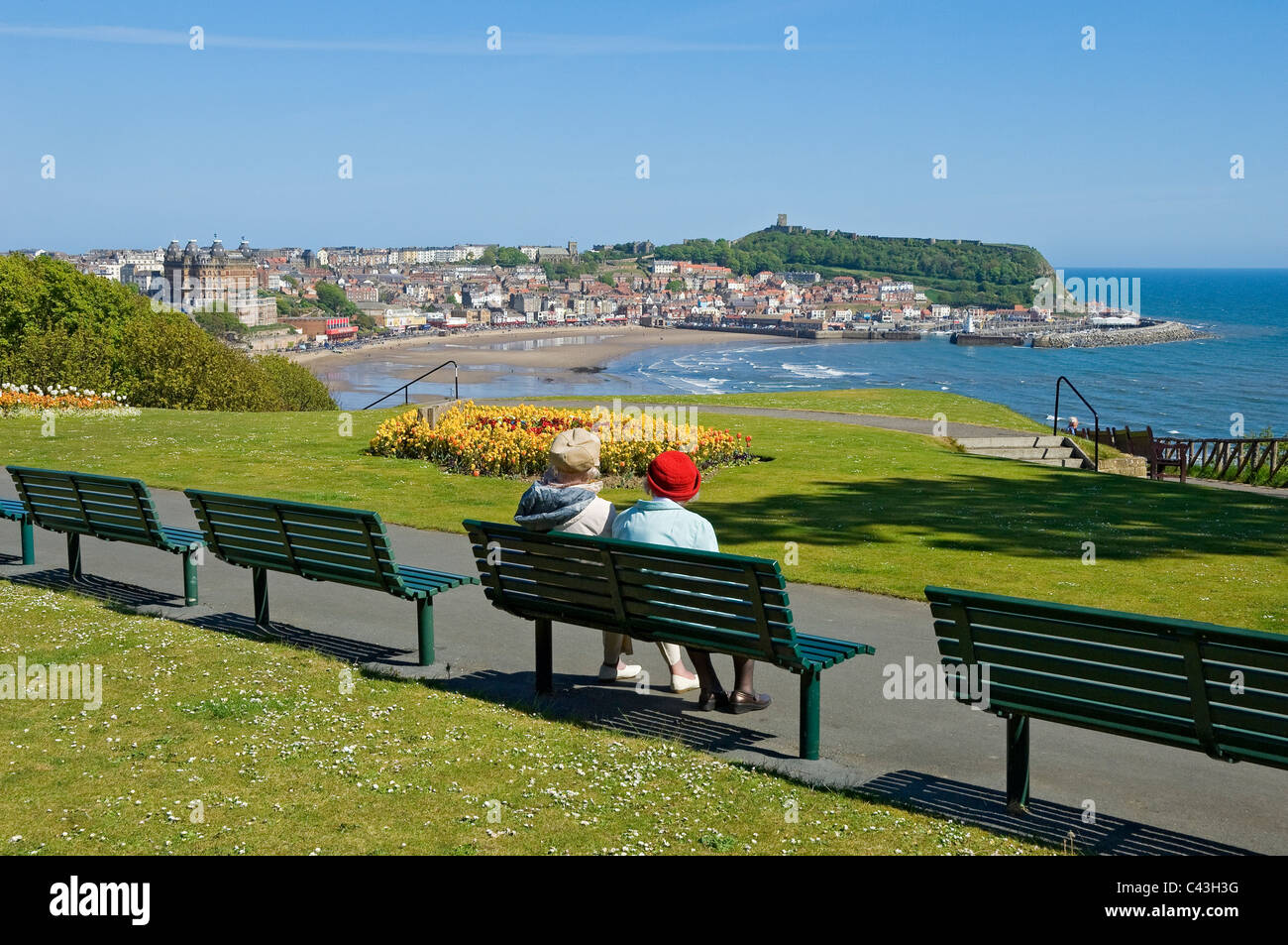2 Older senior people sitting on bench looking towards South Bay beach Scarborough North Yorkshire England UK United Kingdom GB Great Britain Stock Photo