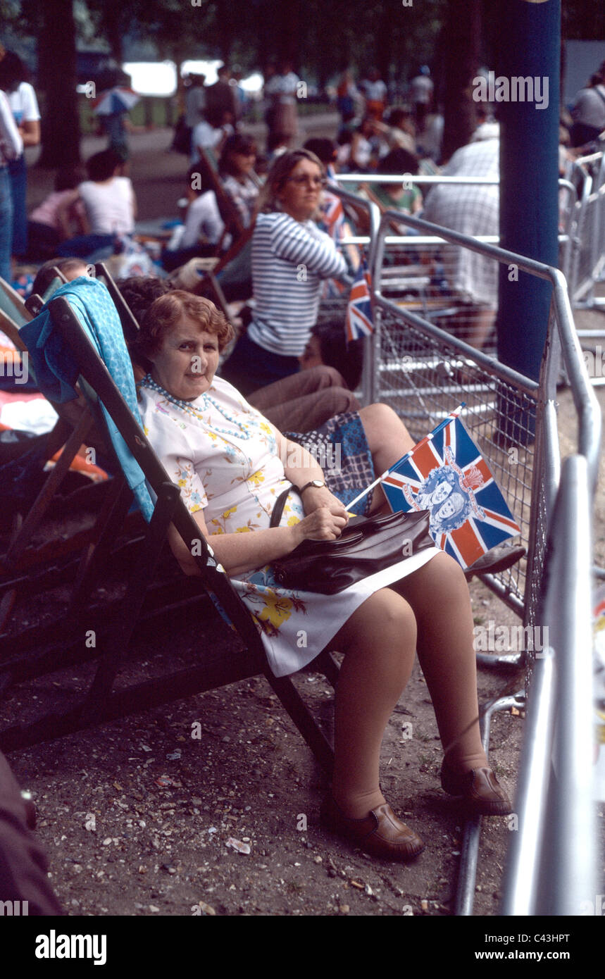 Royalist fan sitting on deck chair in Pall Mall  holding British flag ready to view Prince Charles Princess Diana wedding Stock Photo