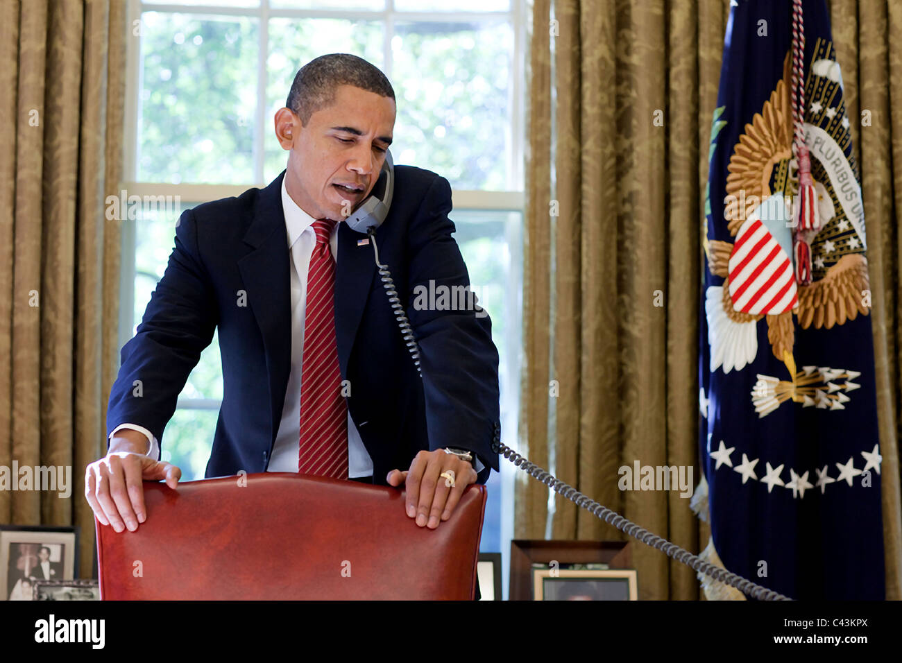 President Barack Obama talks on the phone behind the Oval Office desk
