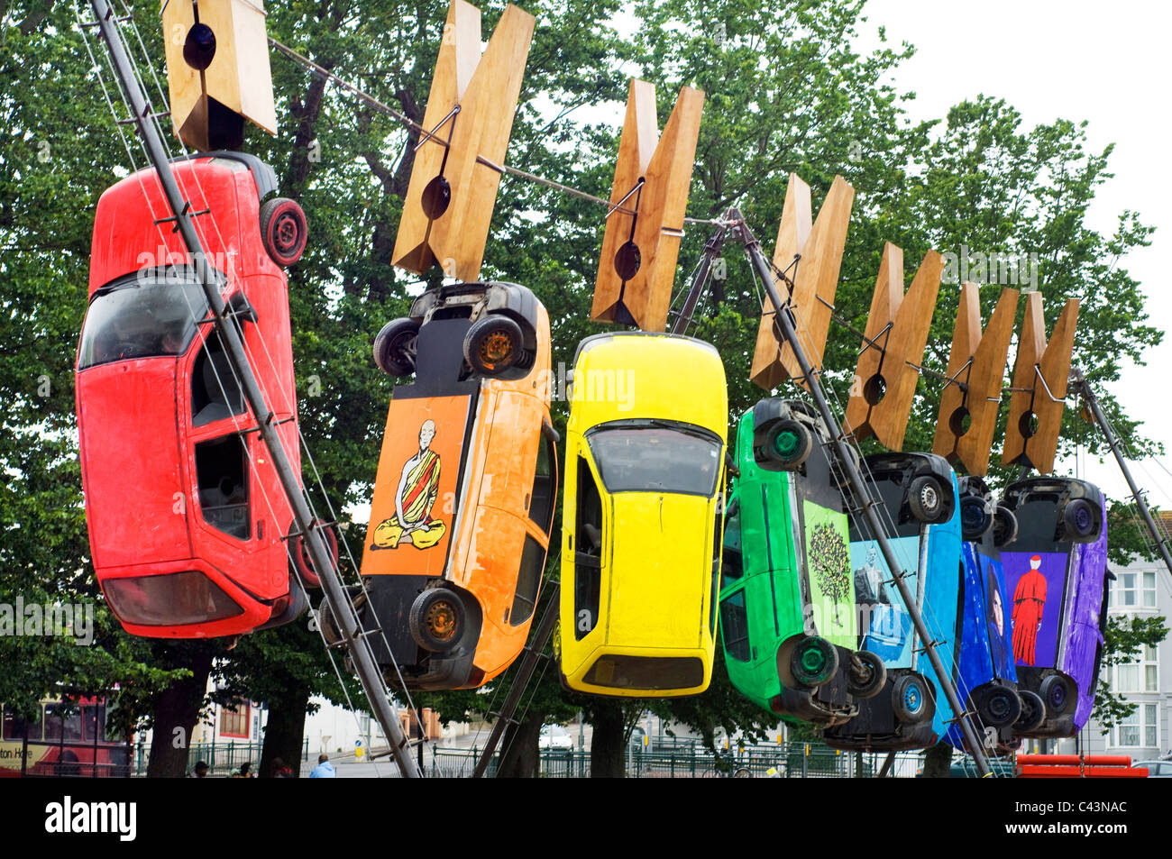 Seven cars hang from giant clothes pegs on a wire in Brighton as part of the annual Art Festival Fringe street theatre. Stock Photo