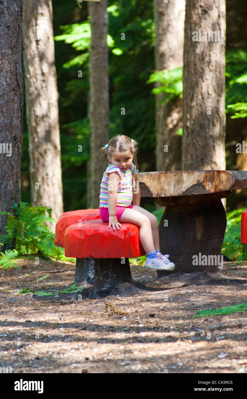 Young female child sulking in the woods sat down Stock Photo
