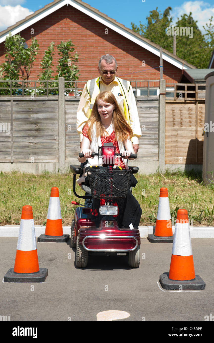 A young disabled girl undergoes training in the safe use of a mobility scooter at the Centre for Disability studies in the UK. Stock Photo