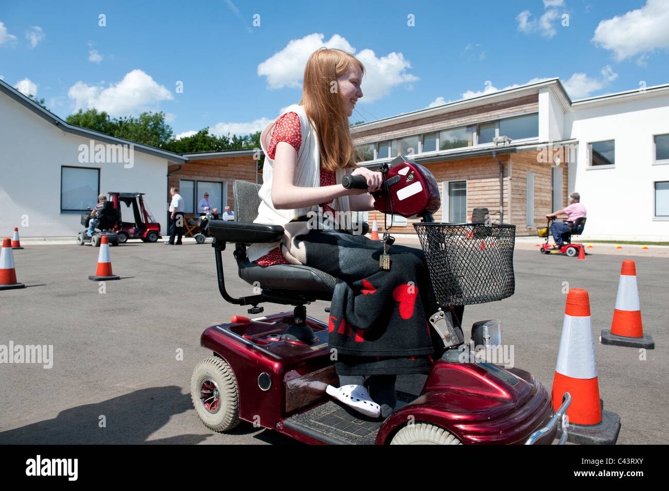 A young disabled girl learning to ride a mobility scooter safely at the Centre for Disability Studies in Rochford, Essex, UK. Stock Photo