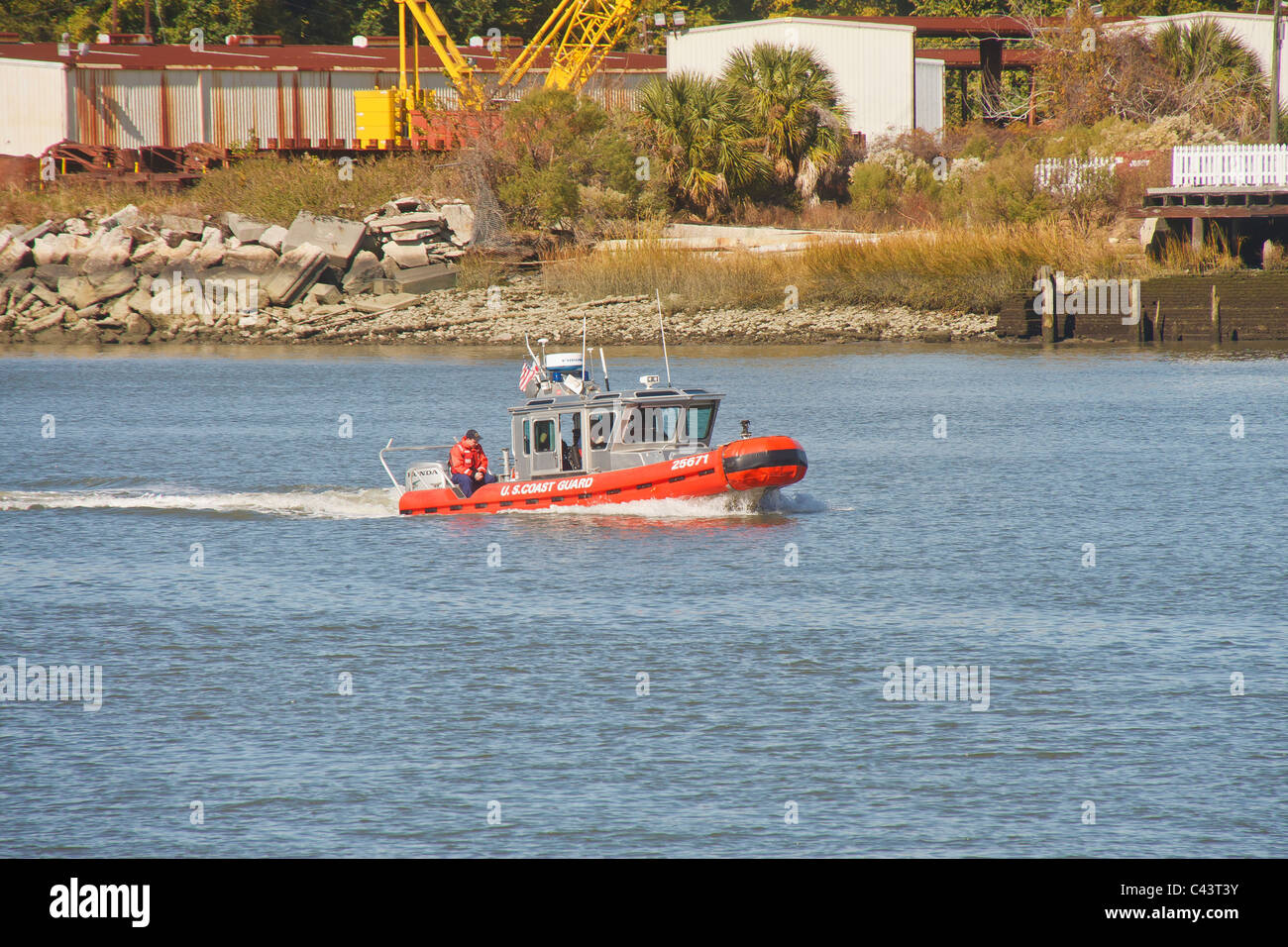 An inflatable coast guard boat patrolling a river near an industrial
