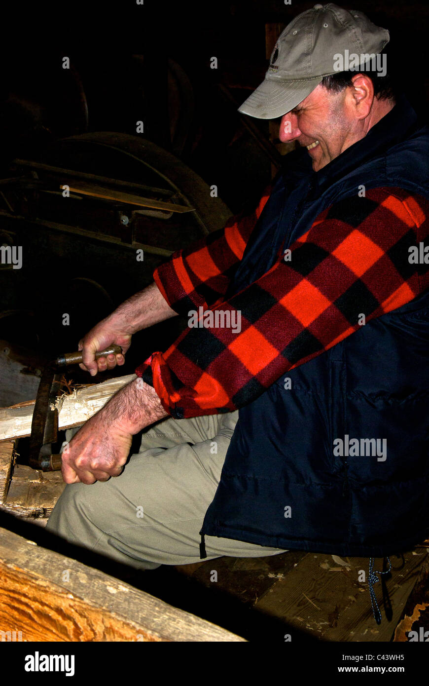 Tour guide Forestry Museum Grandes Piles Quebec using antique spoke shave to hand shape wooden shingles Stock Photo
