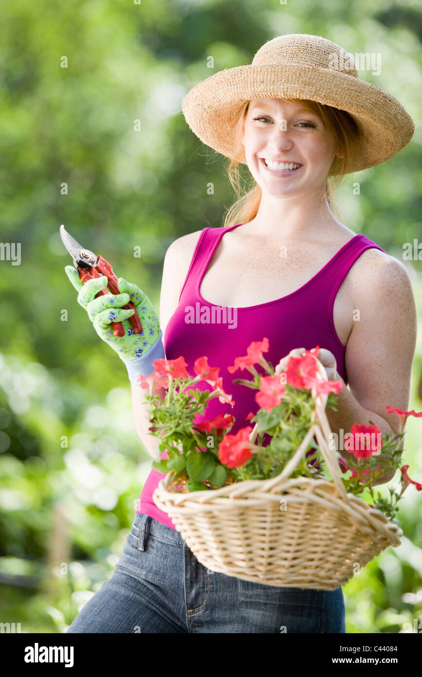 Smiling young woman cutting flowers in her garden Stock Photo