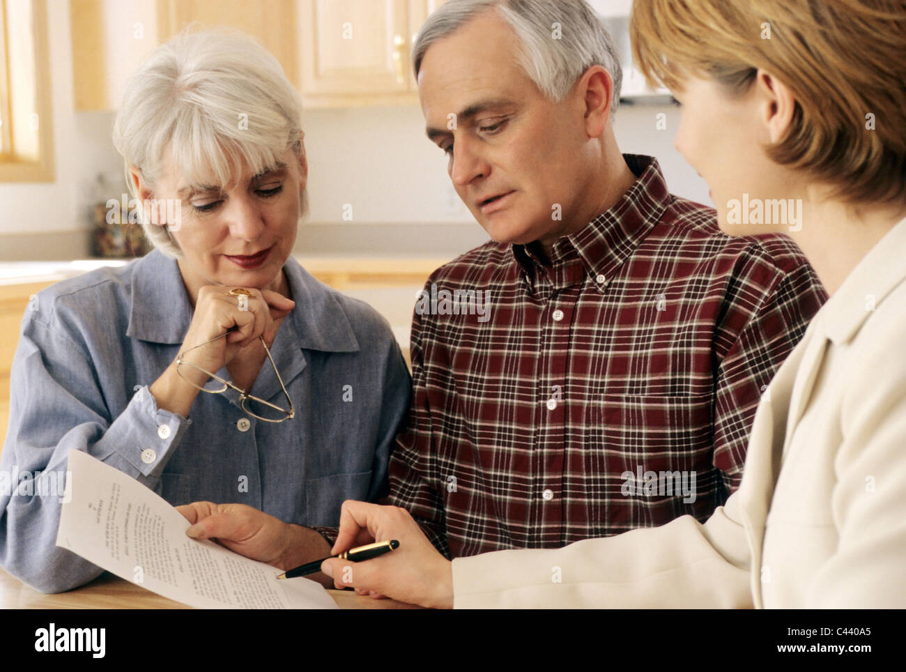 Mature couple talking to financial planner at home Stock Photo