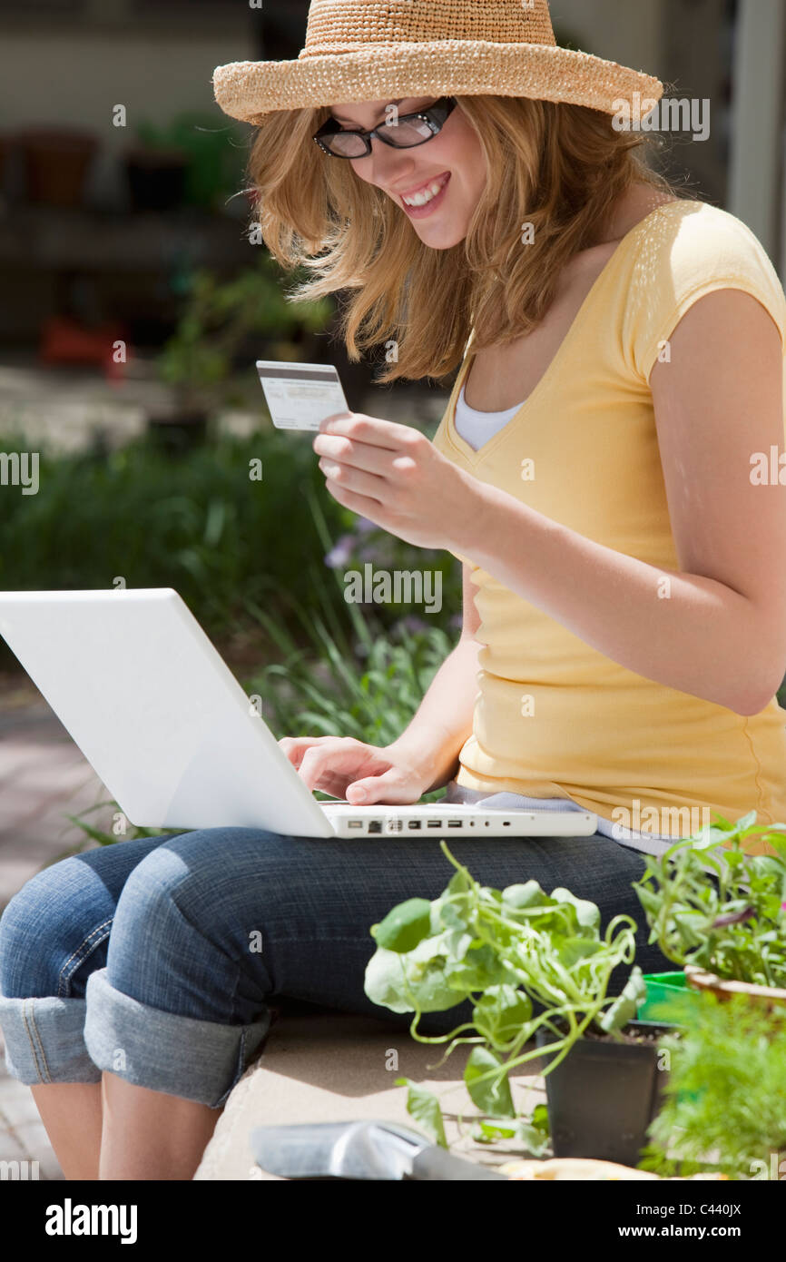 Smiling gardener shopping online with credit card and laptop outside Stock Photo
