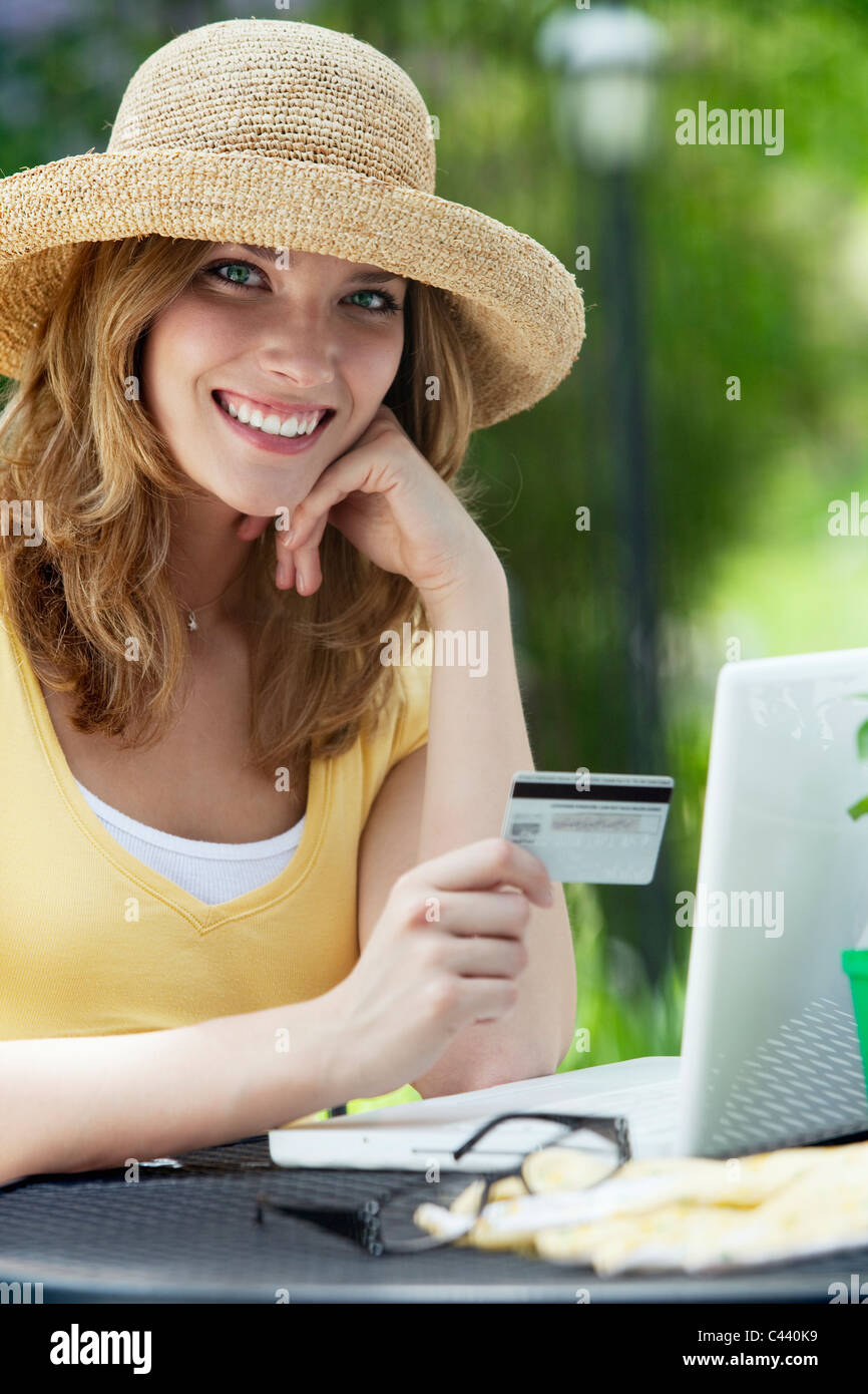 Smiling woman shopping online with credit card and laptop outside Stock Photo
