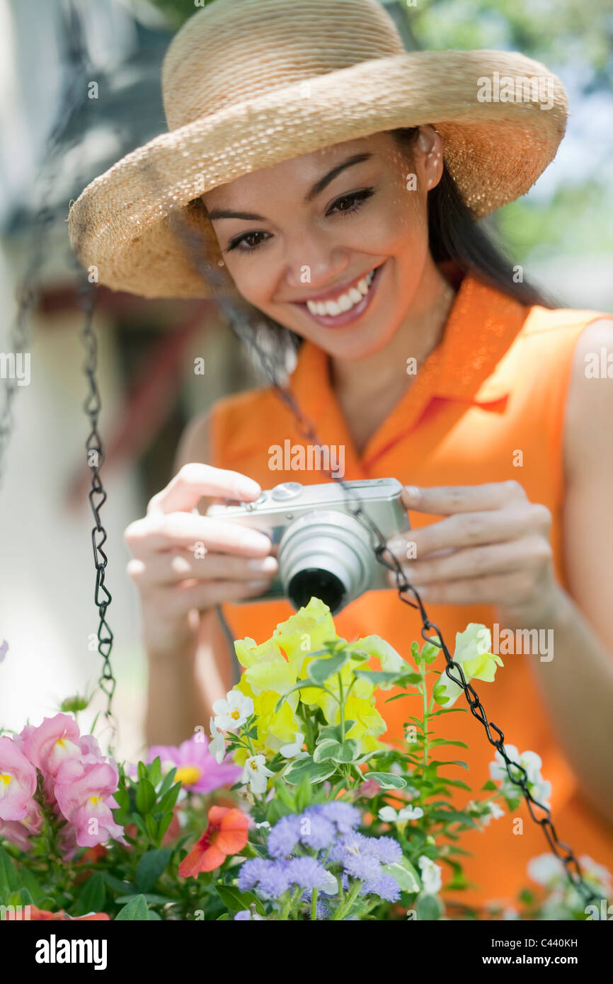Pretty Hispanic woman taking pictures of flowers in the garden Stock Photo
