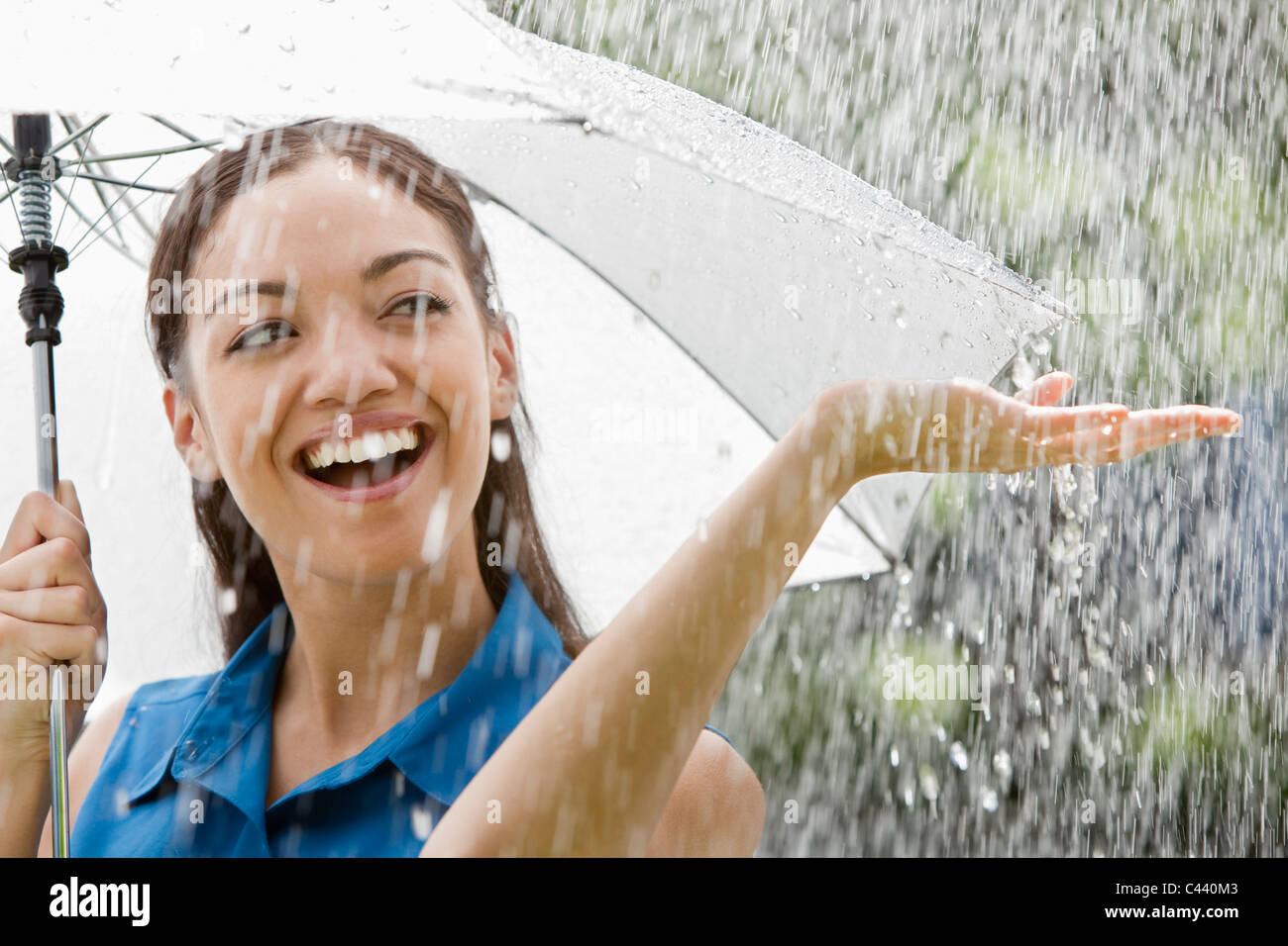 Beautiful Hispanic woman holding umbrella out in the rain Stock Photo