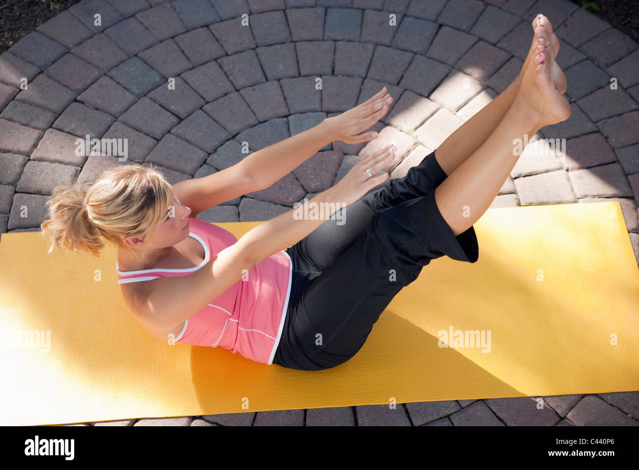 Woman practicing Pilates outside on a yoga mat Stock Photo