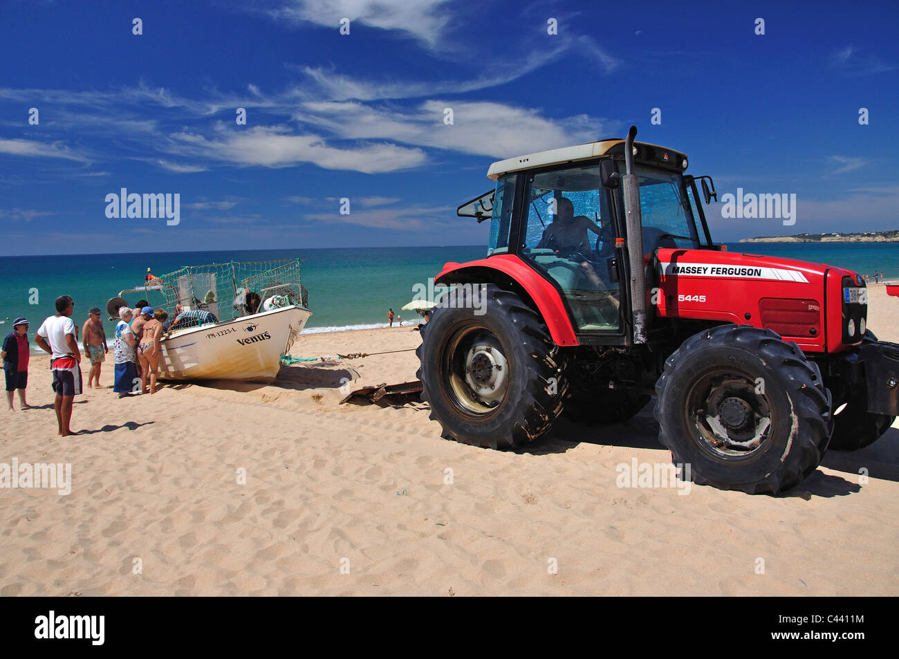 Tractor pulling fishing boat out from sea, Armação de Pêra, Algarve Region, Portugal Stock Photo