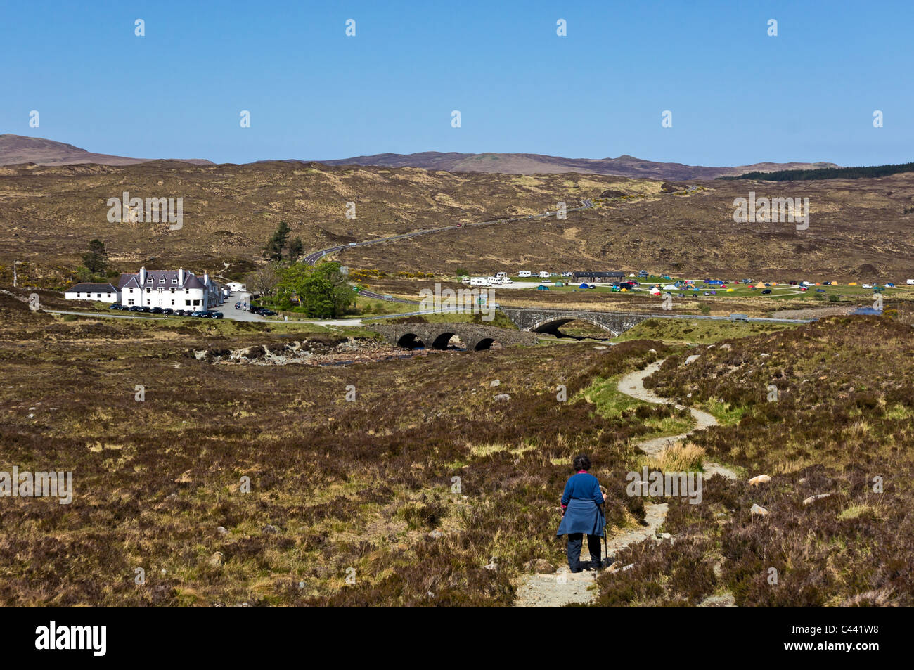 A walker heads towards Sligachan Hotel in Glen Sligachan Skye Scotland with old and new bridges in centre of picture Stock Photo