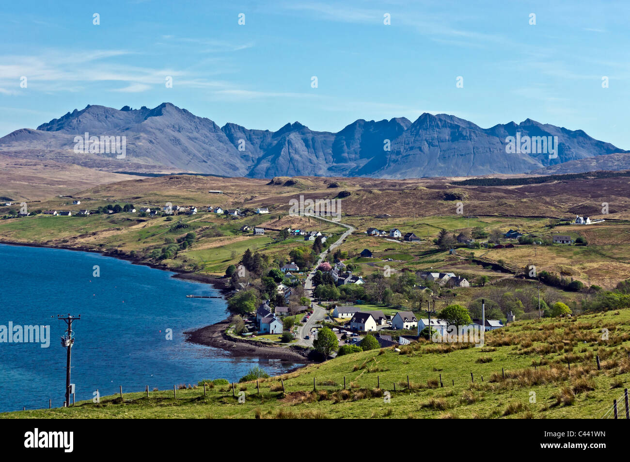 View from above Skye village Carbost towards the Cuillin Hills with Talisker Whisky distillery in the foreground. Stock Photo